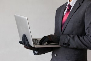 Business man wearing gloves and using computer - fraud concept