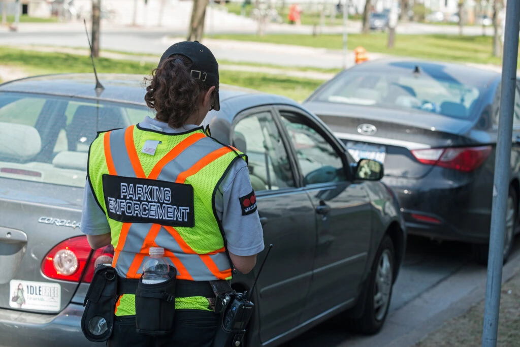 Halifax, Canada - A parking enforcement official with Securitas writes parking ticket for vehicle at expired street meters.